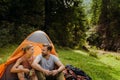 Young travelers resting in tents while hiking in green forest