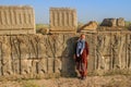 Young woman tourist with a head covered stands on the background of the famous bas-reliefs of the day capital of Persia Iran - P