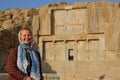 Young woman tourist with a head covered stands on the background of the famous bas-reliefs of the day capital of Persia Iran - P