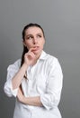 White young woman in a white shirt pondered against a gray