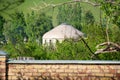 White yurt among green trees on a hill. Asian traditions