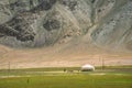 White yurt and a woman on pastures at the foot of the mountain