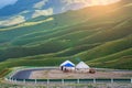 White yurts beside roadside with the green wriggle of the mountains