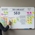 Whiteboard displays a detailed SEO checklist with headers and key sections in blue Royalty Free Stock Photo