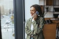 Whitecollar worker chatting on cell phone by window in office building