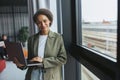 A whitecollar worker in formal wear holds a laptop by a window at a building