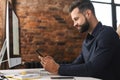 A whitecollar worker is seated at a wooden desk, using a cell phone