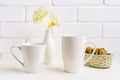 Whites cappuccino and coffee latte mug mockup with yellow orchid in vase and cookies in wicker basket Royalty Free Stock Photo