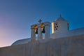 Whitewashed Greek Orthodox chapel, small belfry with cross and bell, roof and dome at sunset sky background. Close-up Royalty Free Stock Photo