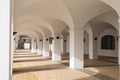 Whitewashed portico with many arches and a patterned stonework floor