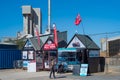 Whitstable, UK - Apr 4 2023 Small huts selling boating trips in Whitstable harbour in front of the iconic Brett Aggregates tower