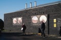 A man with his dog and a senior woman walk by the iconic black wood on the back of the buildings