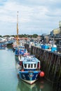 Colourful fishing and tourist boats in Whitstable harbour at low tide