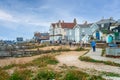 Tourists and locals walk along the wooden seafront pathway in front of the distinctive architecture