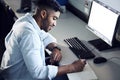 An IT whiz in the making. a young man writing in a notebook and using a computer at college. Royalty Free Stock Photo