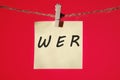 Who, German word for Who, (German: Wer) text on a yellow sticker hanging on a rope with clothespins on a red background