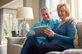 Who knew technology would simplify life so much. a happy mature couple relaxing on the sofa and using a digital tablet