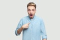 Who? me? Portrait of shocked handsome young man in light blue shirt standing, pointing himself and looking at camera with Royalty Free Stock Photo