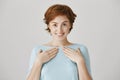 Who, me, thank you. Portrait of happy charming redhead girl with short haircut standing in light-blue blouse and
