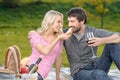 Who is the most hungry? Beautiful young woman feeding her boyfriend with a sandwich on the picnic