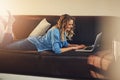 Who needs a desk when youre a blogger. a relaxed young woman using a laptop on the sofa at home. Royalty Free Stock Photo