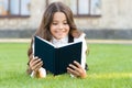 Who needs rest when theres another book to be read. Adorable small child read book on green grass. Cute little girl Royalty Free Stock Photo