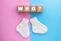 WHO text on wood cubes and pair of cute knitted socks on pink-blue background. Gender of the baby. Boy or girl. Waiting foa a Royalty Free Stock Photo