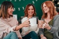 Who thought wed toast with coffee. three attractive women having a coffee on the sofa together at home.