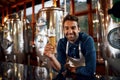 Who would like to have a taste. Portrait of a cheerful young business owner holding up a glass of beer that he just Royalty Free Stock Photo