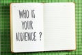 Who is your audience? word on notebook above fence background