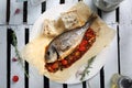 Whole, baked sea bream served with vegetables, on a plate, top view. Roasted fish on a parchment paper. Royalty Free Stock Photo