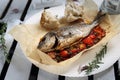 Whole, baked sea bream served with vegetables, on a plate, top view. Roasted fish on a parchment paper. Royalty Free Stock Photo