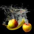 Whole banana, orange, lemon and apple in water on a black background. Fresh fruit with water spray Royalty Free Stock Photo