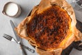 Whole basque burnt cheesecake in baking dish with cream and cutlery on concrete table. top view. Spanish food