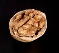 A whole beautiful walnut kernel in half a walnut shell on a black Royalty Free Stock Photo