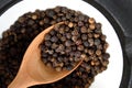 Whole black pepper in a bowl and wooden spoon Royalty Free Stock Photo