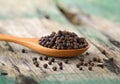 Whole black pepper on wooden spoon Royalty Free Stock Photo