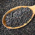 Whole black urad beans in wooden spoon closeup