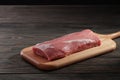 Whole boneless pork loin without fat. Pork tenderloin on a cutting board on a dark background Royalty Free Stock Photo