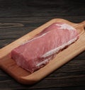 Whole boneless pork loin without fat. Pork tenderloin on a cutting board on a dark background Royalty Free Stock Photo