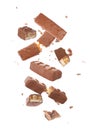 Whole and broken chocolate bars with caramel, nuts and nougat falling on white background Royalty Free Stock Photo