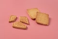 Whole and broken square cookies lies on pink desk on kitchen
