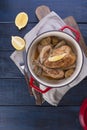 The whole chicken baked with lemon and rosemary in a red cast iron. Blue wooden background and gray towel. Knife and fork. Free Royalty Free Stock Photo