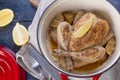 The whole chicken baked with lemon and rosemary in a red cast iron. Blue wooden background and gray towel. Knife and fork. Free Royalty Free Stock Photo