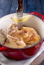 The whole chicken baked with lemon and rosemary in a red cast iron. Blue wooden background and gray towel. The knife is stuck in Royalty Free Stock Photo