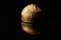 A whole chocolate candy in a golden wrapper on a black background Royalty Free Stock Photo