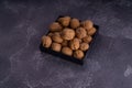 Whole and cracked walnuts on a square plate on blue textured surface, side view. Healthy nuts and seeds composition. Royalty Free Stock Photo