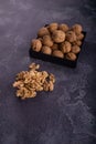 Whole and cracked walnuts on a square plate on blue textured surface, side view. Healthy nuts and seeds composition. Royalty Free Stock Photo