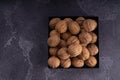 Whole and cracked walnuts on a square plate on blue textured surface, top view. Healthy nuts and seeds composition. Royalty Free Stock Photo