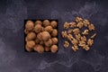 Whole and cracked walnuts on a square plate on blue textured surface, top view. Healthy nuts and seeds composition. Royalty Free Stock Photo